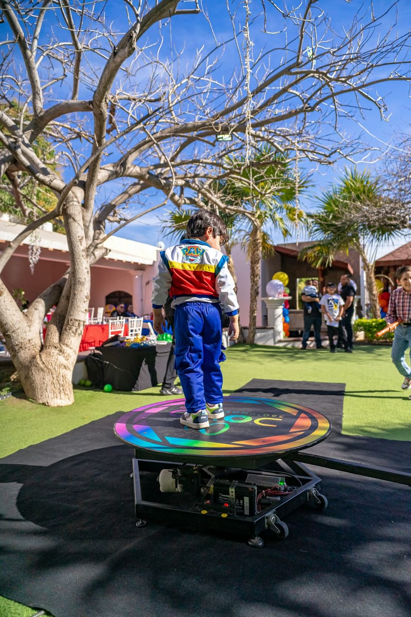 A round spinning platform set up on a lawn at an outdoor party, with a child standing on it