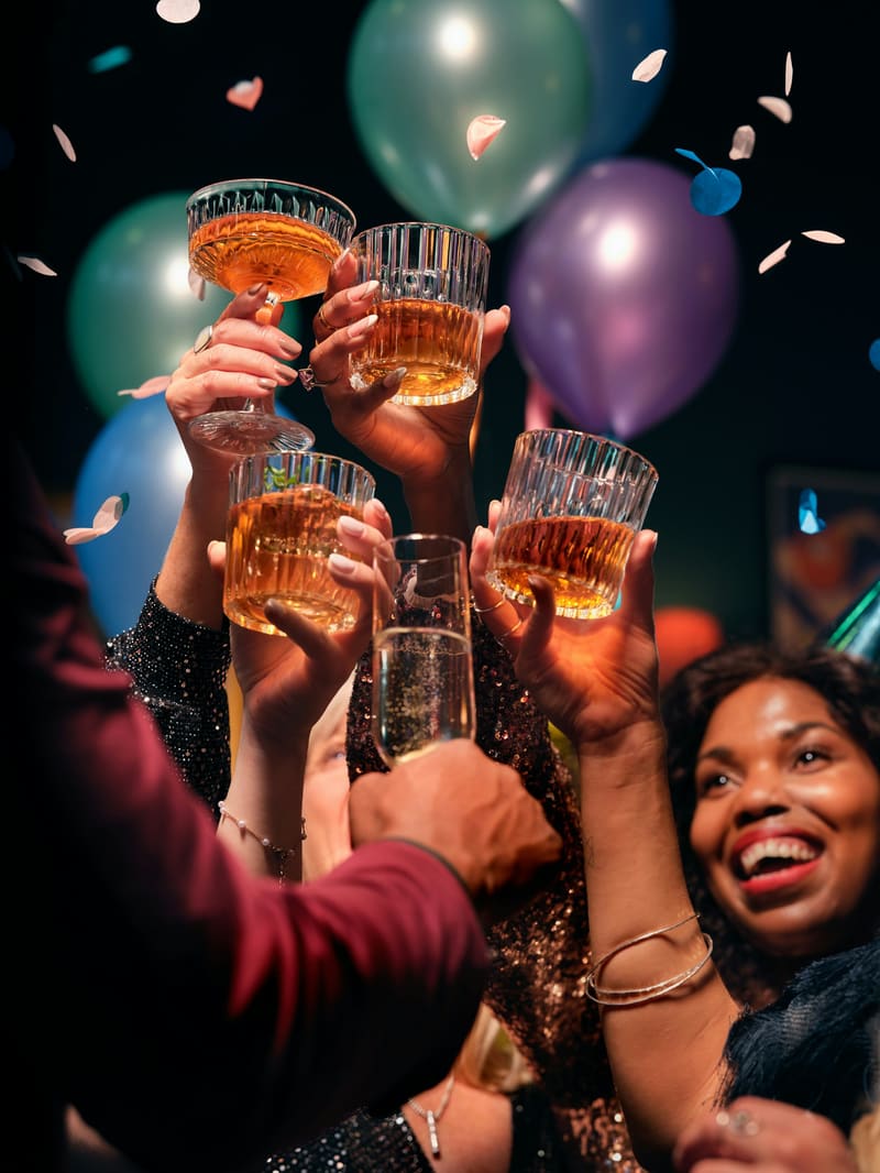 Guests raising glasses in a toast at an evening event, with balloons behind them